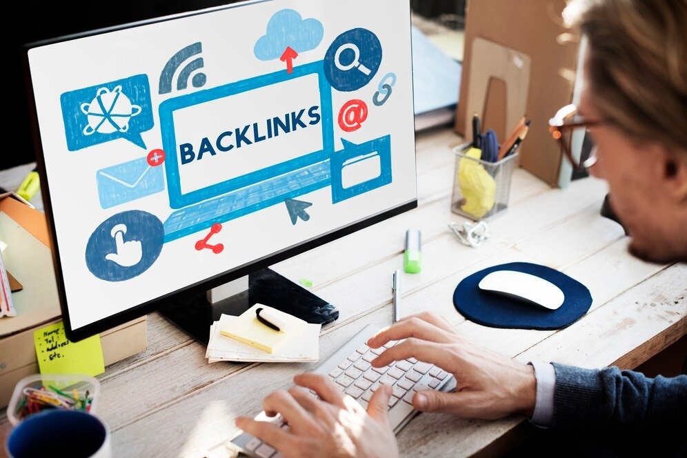 Person working on a computer with a screen displaying the word 'BACKLINKS' along with digital icons, suggesting the concept of SEO and link-building strategies.